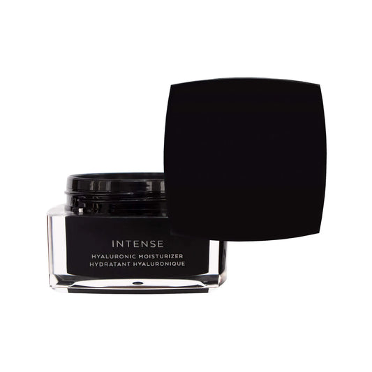 Open black glass jar of The Barrier Balm moisturizer with the lid resting beside it, showing the creamy texture inside